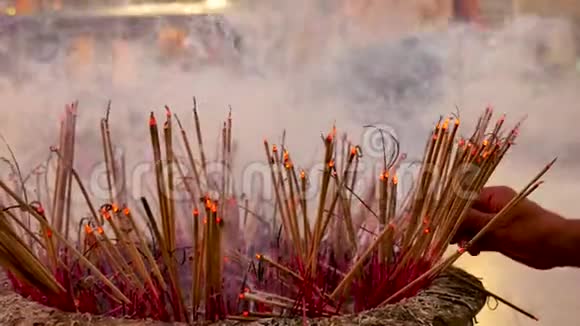 传统的火焰点燃香棒在佛教寺庙中祈祷火焰蜡烛用烟香棒燃烧温暖的光视频的预览图