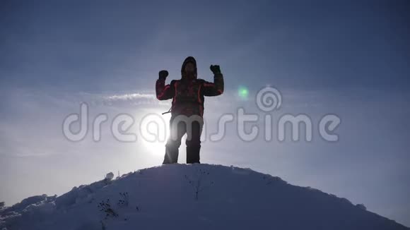 旅行者在白雪皑皑的山顶上为他的胜利而欢欣鼓舞跳跃和挥动他的手臂一个快乐的人快乐的游客视频的预览图