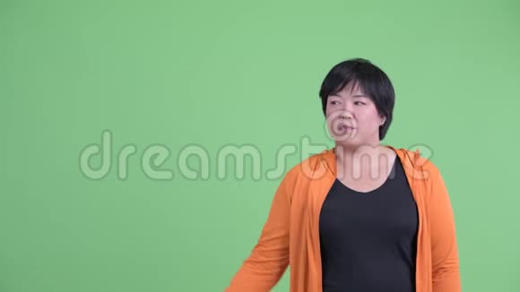 站着的年轻超重的亚洲女人指着准备去健身房视频的预览图