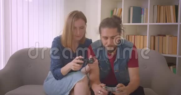 这对年轻夫妇用操纵杆玩电子游戏女孩赢了就开心了视频的预览图