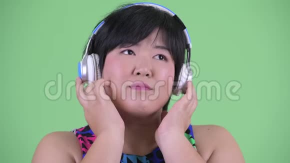 年轻体重超重的亚洲女性听音乐的脸视频的预览图