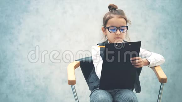 一个女老板坐在椅子上拿着一个文件夹和一支铅笔灰色背景特写镜头写一支铅笔视频的预览图