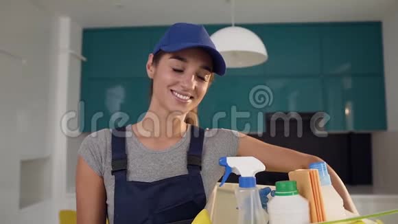 愉快的清洁服务妇女拿着装有特殊清洁剂的盒子和喷洒物品进行清洁站在里面视频的预览图