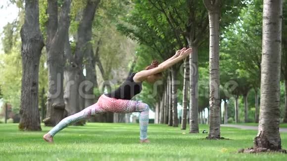 一个女孩站在一个瑜伽姿势中在大自然中缓慢地运动着视频的预览图