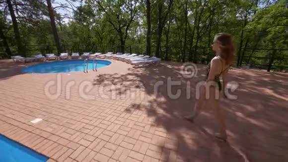 年轻女子穿着时尚泳衣正在夏天进入游泳池视频的预览图