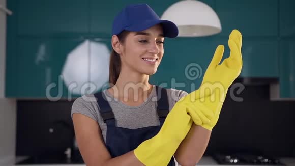 美丽的微笑女人从清洁服务戴着防护手套清洁蓝黑色厨房视频的预览图