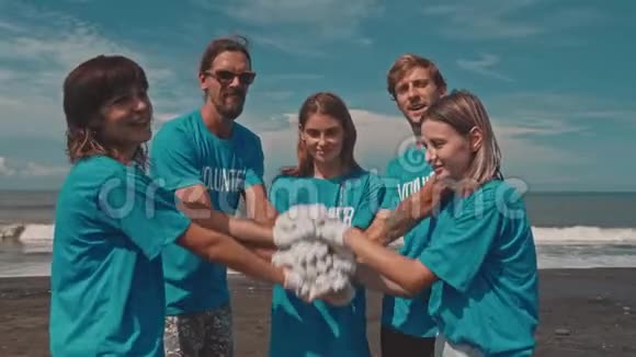 团体志愿者把手放在上面作为清理海滩的统一象征视频的预览图