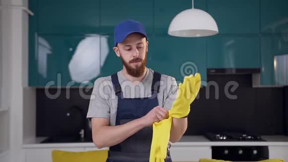 穿着清洁厨房工作服的大胡子青年戴上黄手套视频的预览图