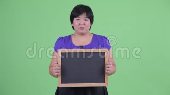 快乐的年轻超重的亚洲女人拿着黑板思考视频的预览图