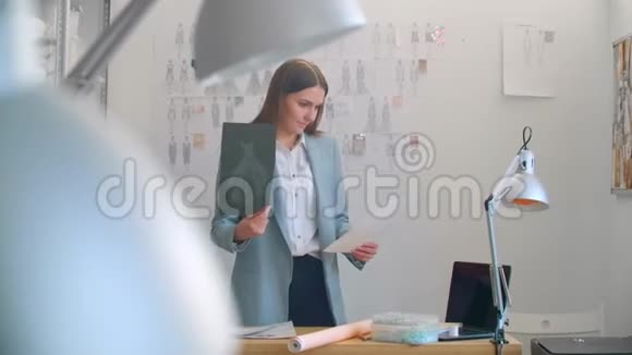 年轻的时装设计师站着背对着相机看挂在墙上的素描女人在想视频的预览图