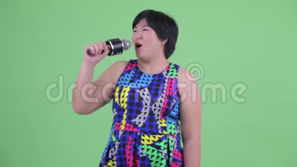 快乐的年轻肥胖的亚洲女人用麦克风唱歌准备聚会视频的预览图