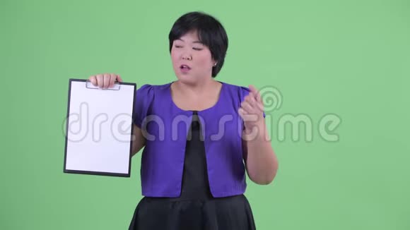 一位身材矮小体重超重的亚洲女性她展示剪贴板并竖起大拇指视频的预览图