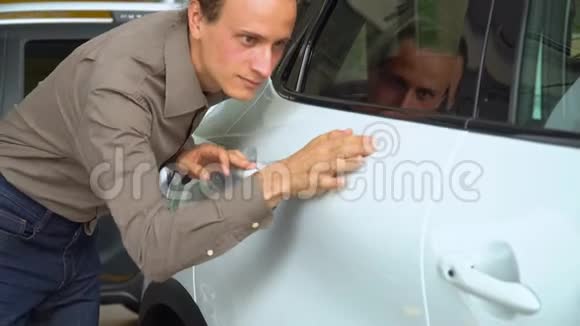 一个男人在汽车经销店里检查一辆白色的车视频的预览图