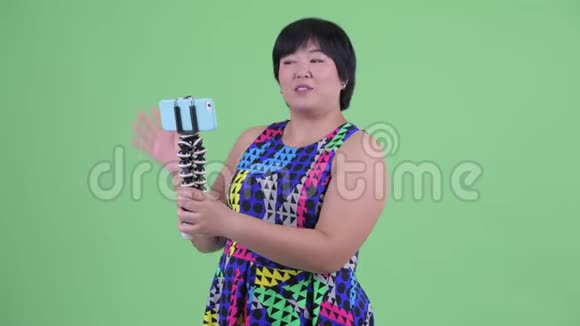 快乐的年轻超重的亚洲女人vlog和显示手机准备聚会视频的预览图