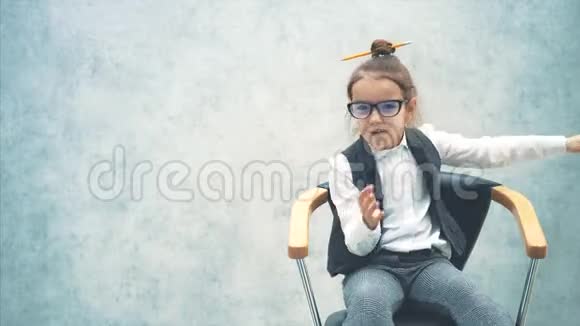 灰色背景的小商业女孩在这悲伤的坐在椅子上他挥舞着双手举起手视频的预览图