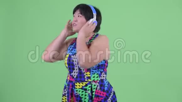 快乐年轻超重的亚洲女人听音乐跳舞视频的预览图