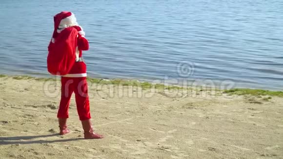 圣诞老人在海边或湖边背着一个礼品袋视频的预览图
