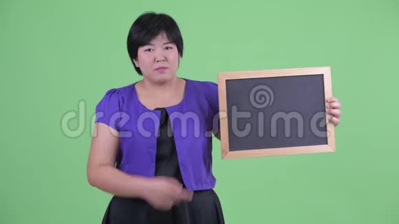 穿着衣服的年轻超重的亚洲女人拿着黑板竖起大拇指视频的预览图
