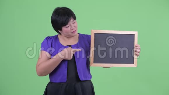 快乐年轻超重的亚洲女人拿着黑板竖起大拇指视频的预览图