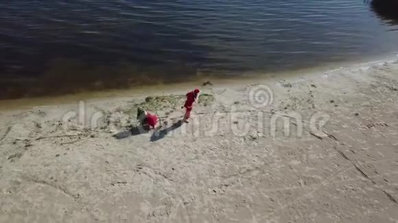 圣诞老人拉着雪橇带着一袋礼物和一棵圣诞树沿着湖的沙岸顶部视图视频的预览图
