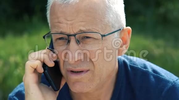 一个穿着蓝色t恤和眼镜头发花白严肃认真的男人坐在船上严格地打电话视频的预览图