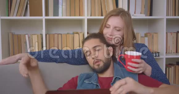 hipster的家伙用手提电脑完成他的工作亲吻他的女朋友并在家里热情地与她交谈视频的预览图