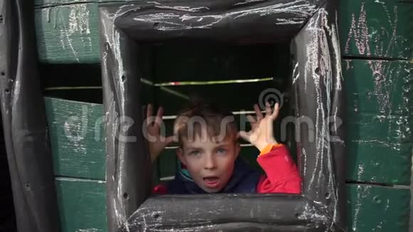 这位小学生从房子的窗户往外看脸上露出鬼脸引人注意视频的预览图
