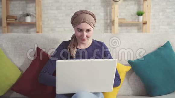 一位戴手提电脑化疗后戴着围巾患癌症的年轻女子的肖像视频的预览图