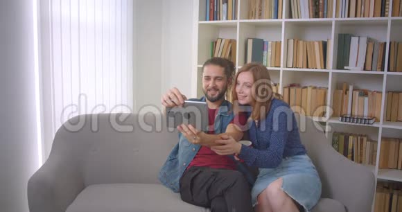 嬉皮青年夫妇在平板电脑上制作自拍照片而盖伊几乎把它掉下来但在家里钓到了视频的预览图
