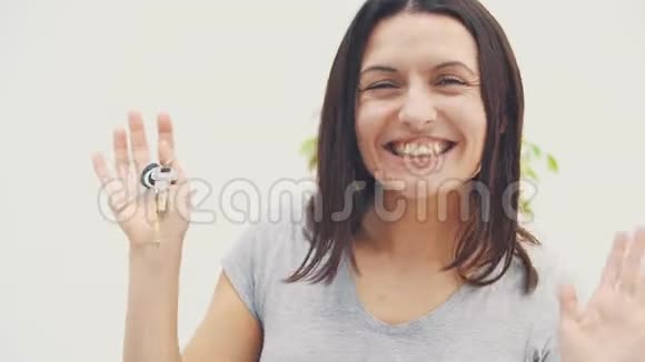 微笑的年轻女子正在展示她的新公寓的钥匙跳舞高兴地挥动她的手视频的预览图