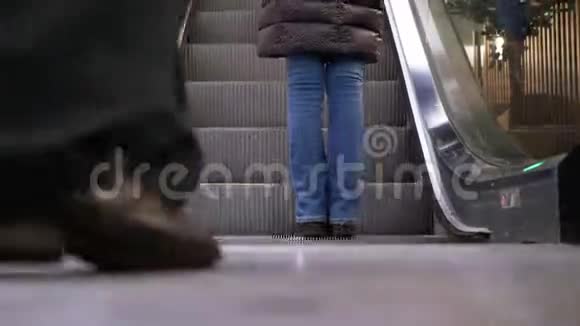 人们的腿在商场的自动扶梯电梯上移动购物中心扶梯上的购物者脚视频的预览图