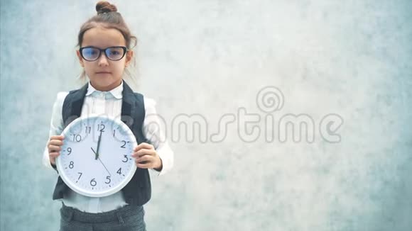 一位年轻漂亮的女老板是灰色背景保持一个白色的时钟显示12小时慢速视频视频的预览图