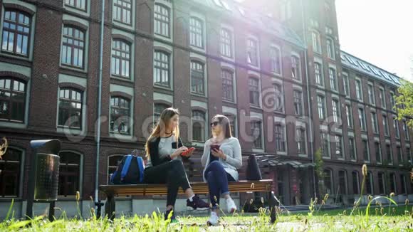 现代女学生在上课前坐在校园公园的长凳上聊天大学朋友视频的预览图