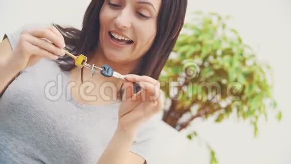 一位笑容可掬的年轻女子正在展示她新公寓的钥匙她在跳舞指着手指看着他们视频的预览图