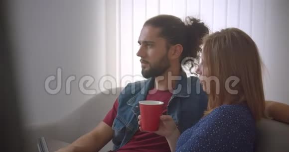 年轻夫妇坐在沙发上在家温柔而亲切地交谈视频的预览图