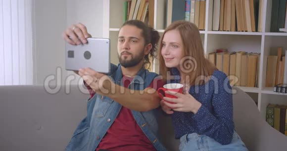 嬉皮青年夫妇在平板电脑上制作自拍照片是积极和漂亮的家视频的预览图