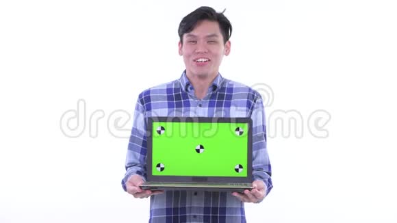 快乐的年轻亚洲时髦男人一边说话一边拿笔记本电脑视频的预览图
