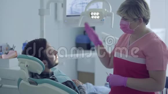 牙医在医疗面具和手套检查她的病人使用手势的情况女性专业医生视频的预览图