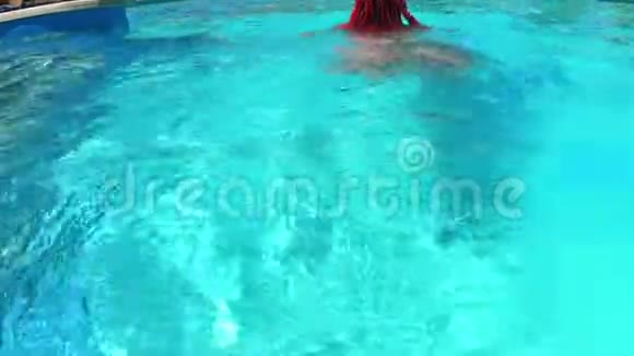 一个晒黑的女人在水上滑梯公园的游泳池里游泳和潜水视频的预览图