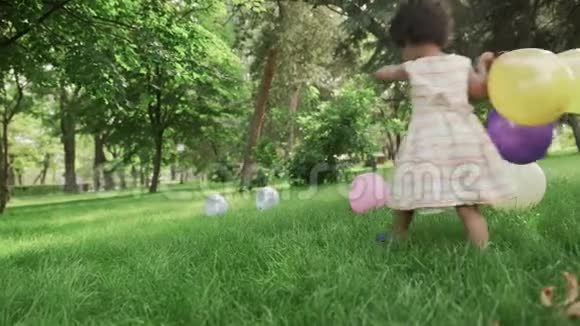 小非裔美国女孩在公园里玩五颜六色的气球视频的预览图