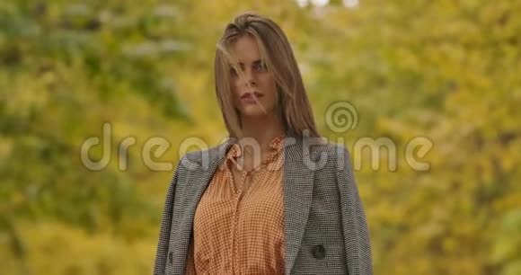 年轻的高加索女人绿色的眼睛站在树叶的背景上看着相机是个漂亮女人视频的预览图
