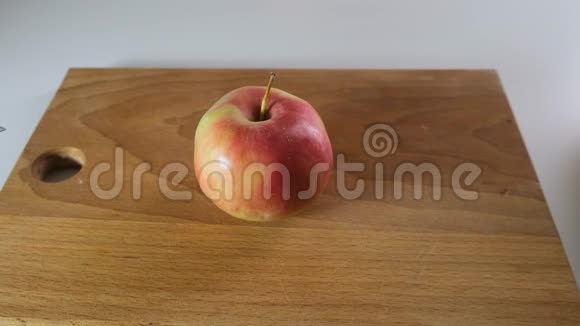 一只手在木板上用刀切一个红苹果视频的预览图