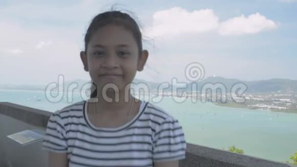 亚洲可爱的女孩穿着休闲装在观景塔上用滑稽的姿势拍照风景迷人视频的预览图