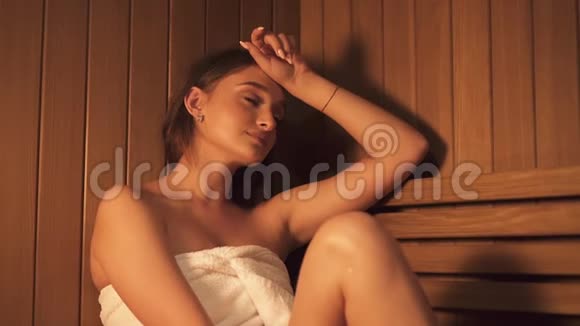 汗流浃背的女人坐在高温的传统桑拿浴室里进行健康治疗和皮肤清洁视频的预览图