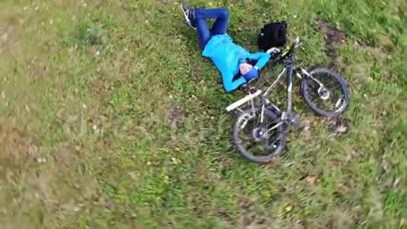 快乐的女人骑着自行车躺在绿草上骑着其他的空中射击鼓舞人心视频的预览图
