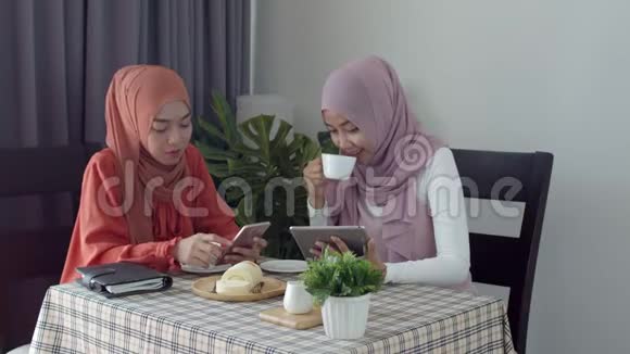年轻的穆斯林工作妇女在咖啡店和朋友讨论视频的预览图
