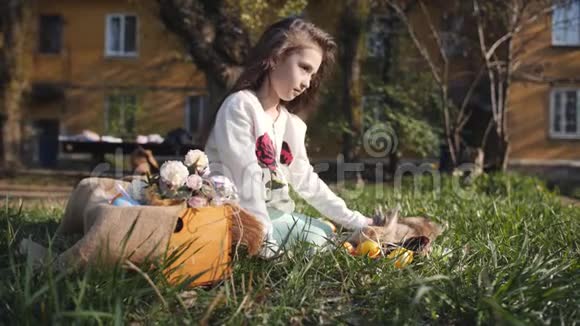 院子里的女孩坐在草地上的毯子上拍拍复活节兔子视频的预览图
