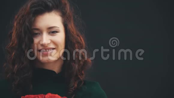 美丽卷曲的黑发女孩站着捧着一束红玫瑰笑得可爱视频的预览图
