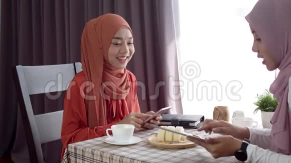 年轻的穆斯林妇女使用智能手机无接触支付咖啡厅视频的预览图
