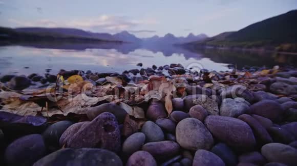 在蒙大拿州的麦克唐纳湖秋天的景象和树叶和岩石的接近视频的预览图
